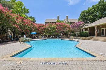 A pool surrounded by trees and bushes with a sign that says